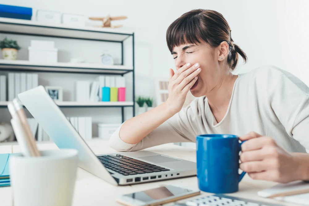 Woman yawning in front of laptop
