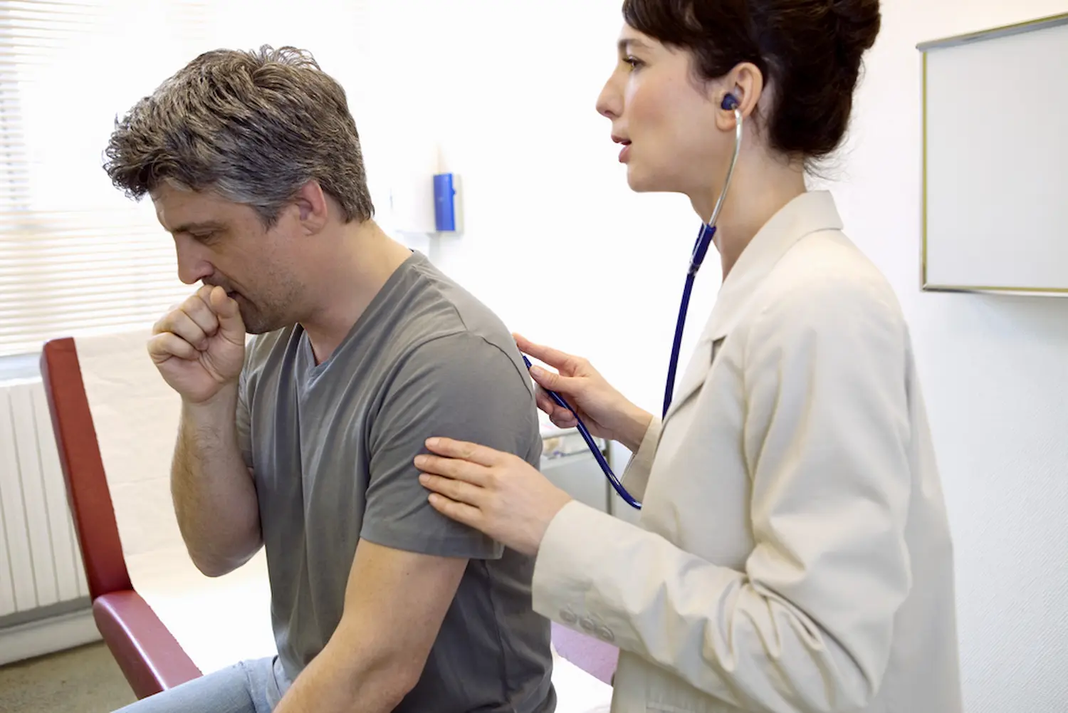 Man with cough getting checked by female doctor