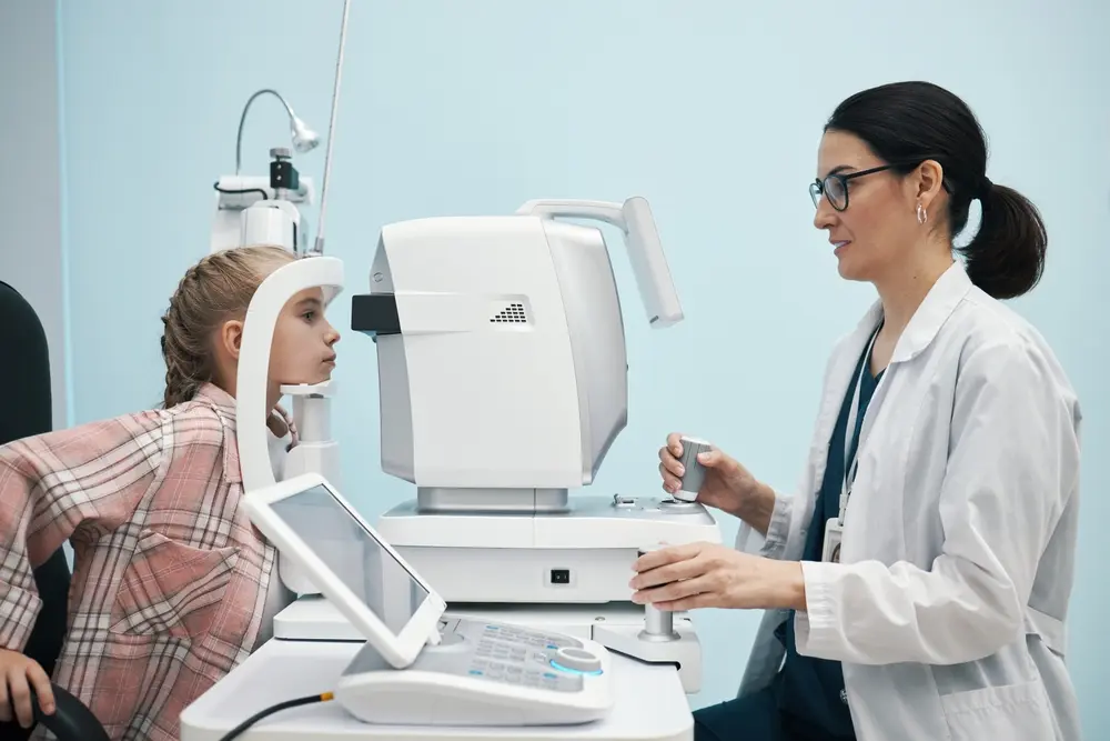 Ophthalmologist checking a young girl's vision using an automated eye exam machine.